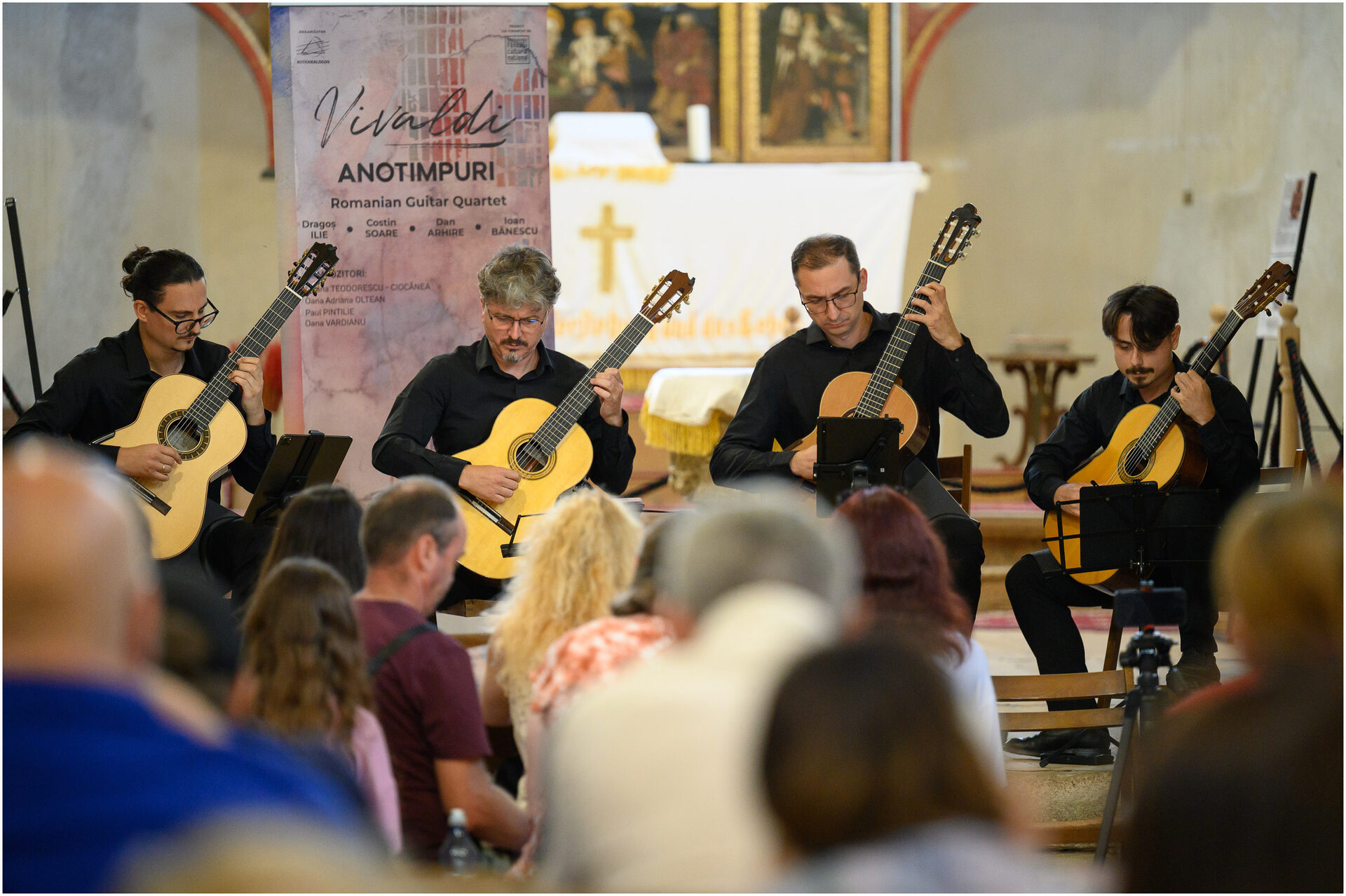 Romanian Guitar Quartet interpretând în fața bannerului turneului „Vivaldi Anotimpuri”.